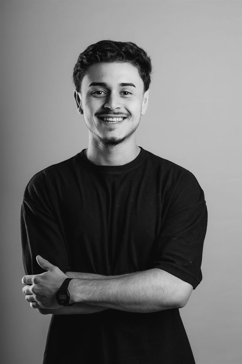 Gustavo Borges sorrindo, de braços cruzados, em foto preto e branco